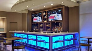 A bar area with a central counter, multiple stools, and shelves with bottles. - SpringHill Suites by Marriott Toronto Vaughan (Vaughan)