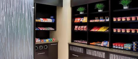 Una cocina moderna con armarios oscuros, electrodomésticos integrados y diversos alimentos en estantes.