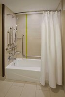 Un baño moderno con bañera, barras de apoyo, ducha y una línea de seguridad verde en la pared.