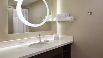 Un baño moderno con un espejo grande, un lavamanos y un perchero para toallas.