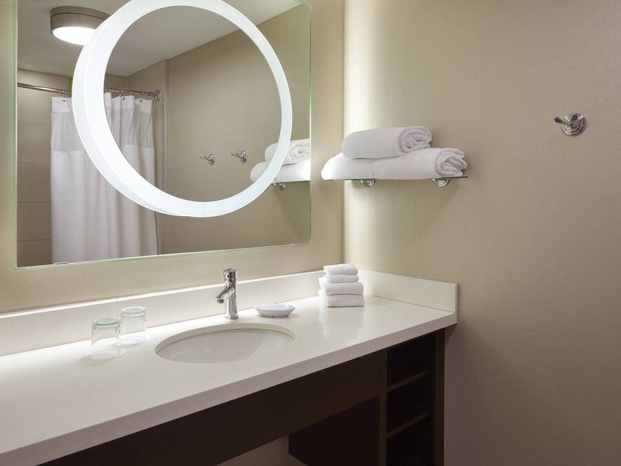 Un baño moderno con un espejo grande, un lavamanos y un perchero para toallas.
