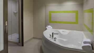 Une salle de bain moderne dotée d’une grande baignoire, d’un espace douche et d’un miroir agrémenté de carreaux verts.