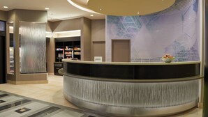 A modern reception area with a curved reception desk, a decorative wall with text, and a patterned floor. - SpringHill Suites by Marriott Toronto Vaughan (Vaughan)