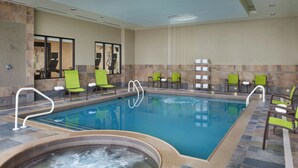 A swimming pool with a hot tub, surrounded by green chairs and a tiled floor. - SpringHill Suites by Marriott Toronto Vaughan (Vaughan)