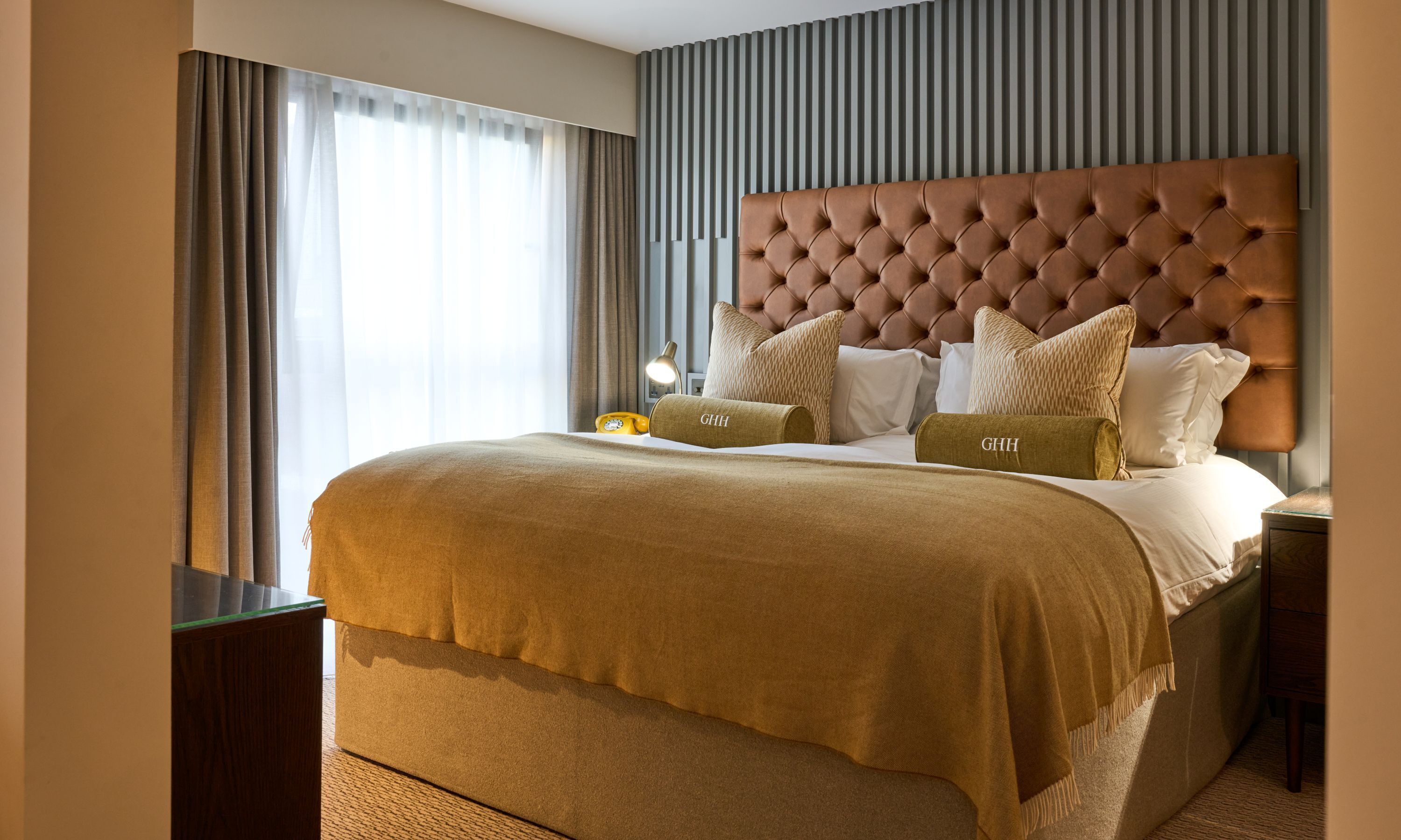A hotel room with a large bed, a headboard, and a bedside table.