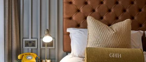 A neatly made bed with a tufted headboard, a bedside telephone, and a lamp on a glass table.