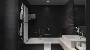 A modern bathroom with a bathtub, two sinks, and a large mirror.