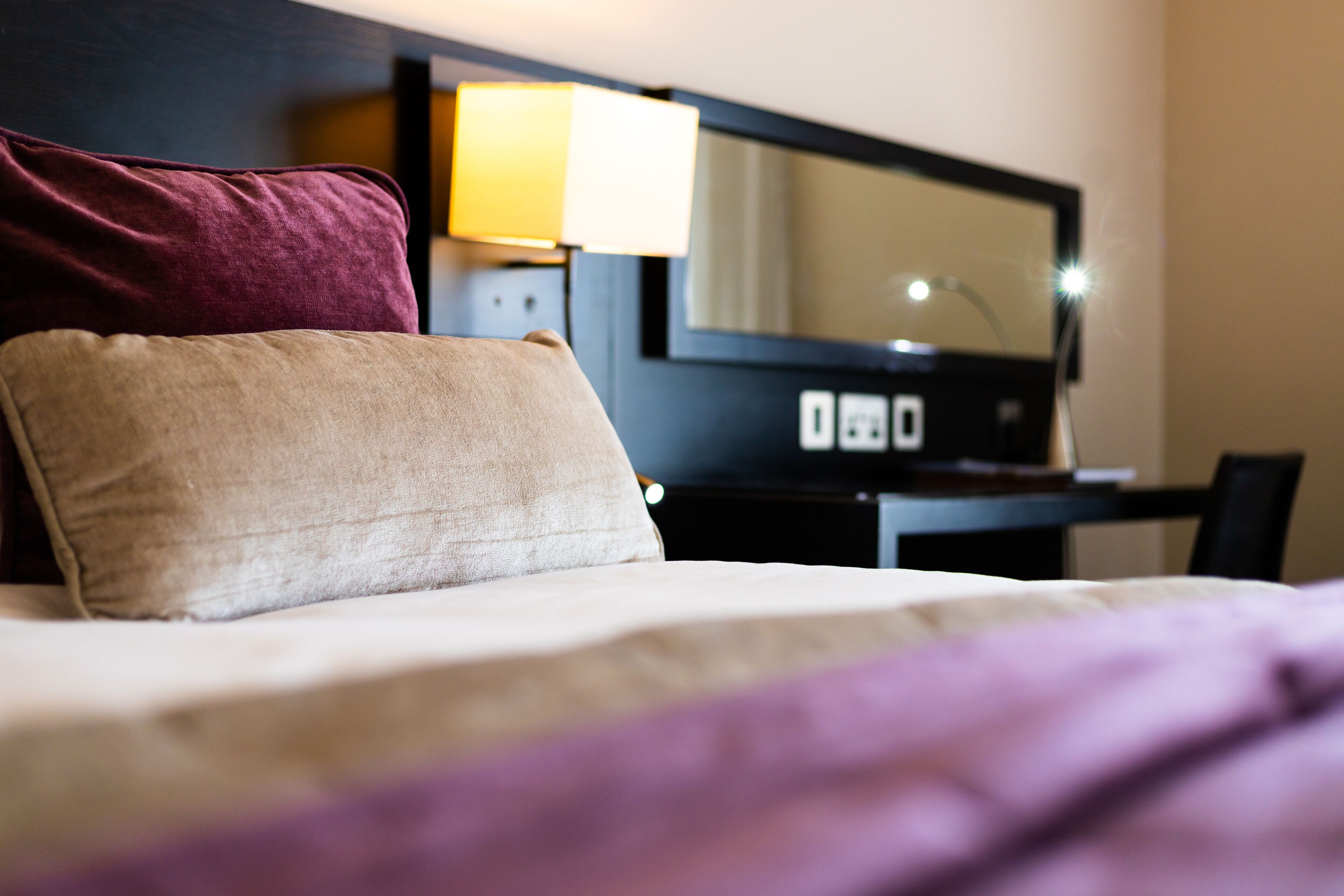 A hotel room with a bed, a desk, and a lamp.