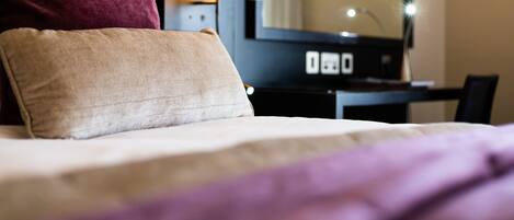 Una habitación de hotel con una cama, un escritorio y una lámpara.