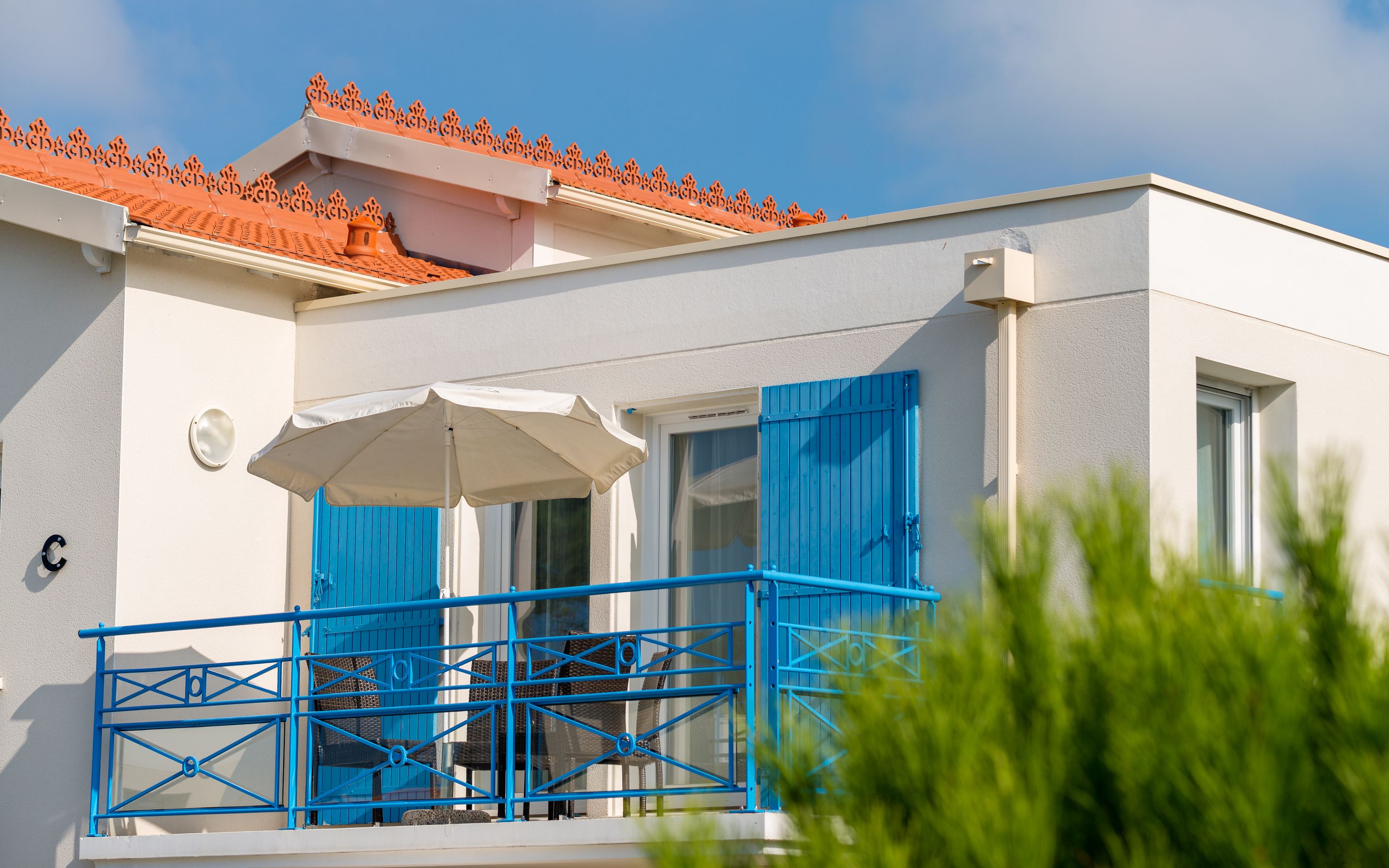 A building with a balcony, blue shutters, and a white awning.