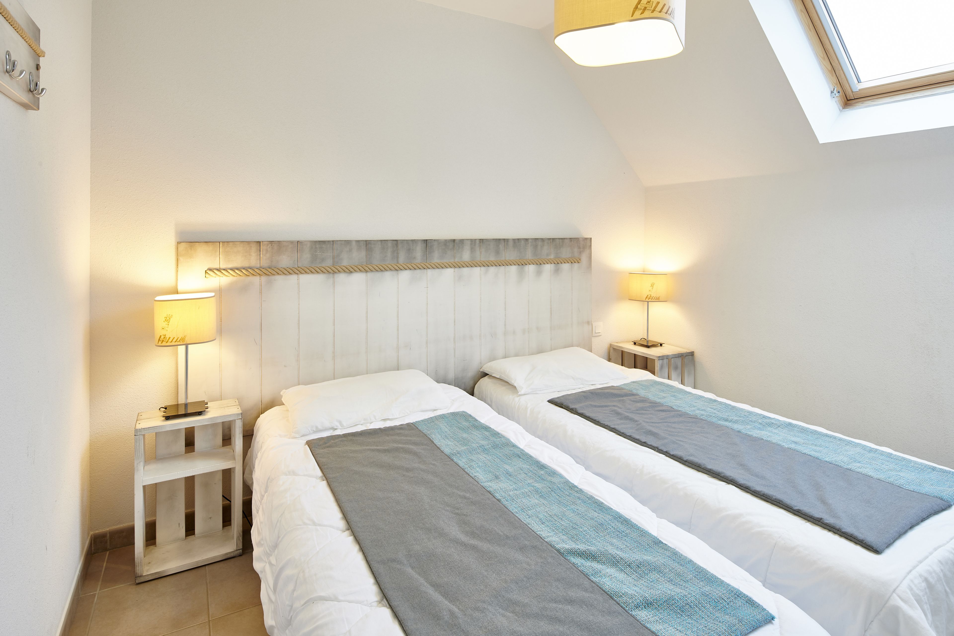 A bedroom with two beds, a sloped ceiling, and a skylight.
