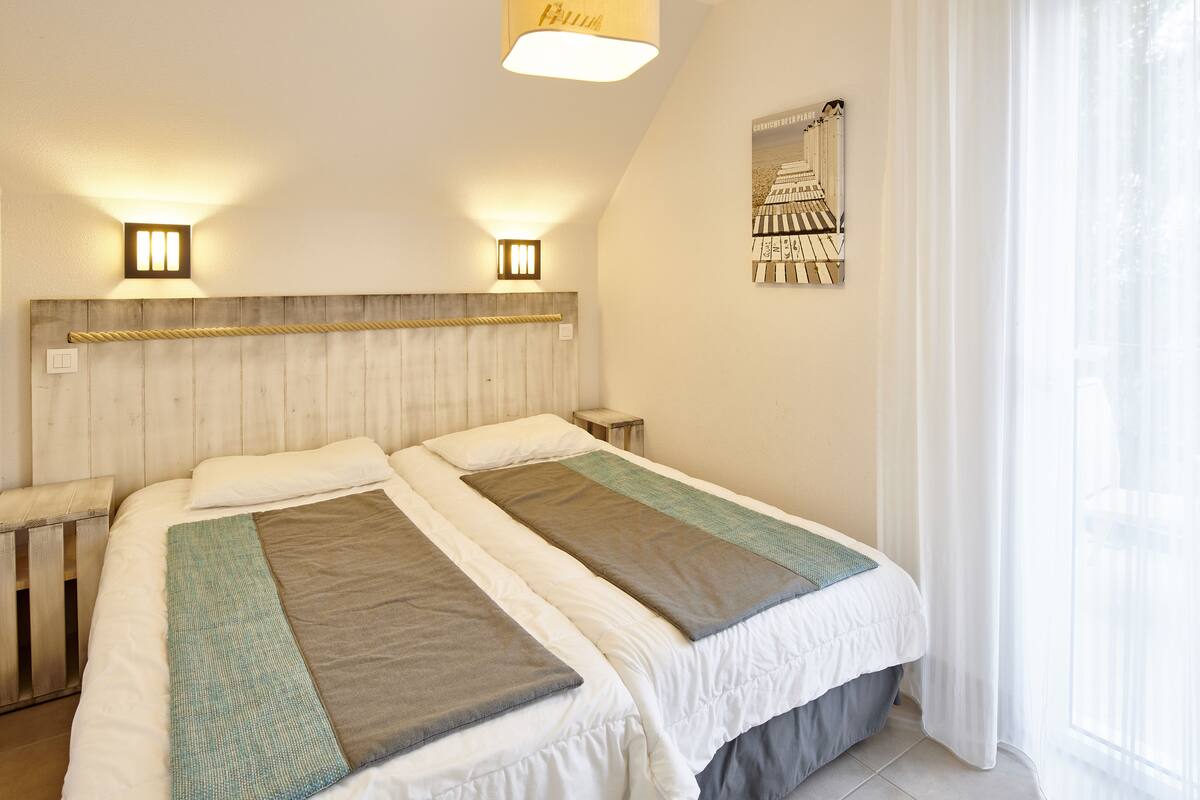 A double bed with a wooden headboard, two bedside tables, and a wall-mounted picture.