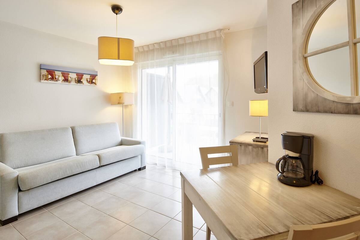 A modern living room with a sofa, a dining table, and a coffee maker.