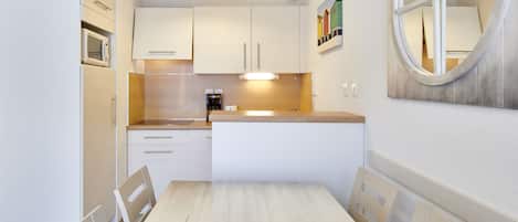 Una cocina moderna con armarios blancos, encimera de madera y una mesa de comedor con sillas.