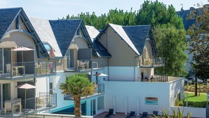 Un hotel de varios pisos con balcones, piscina y zonas de estar al aire libre.
