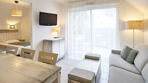 Una sala de estar moderna con un sofá, una mesa de comedor, sillas, un televisor y un ventanal con cortinas.