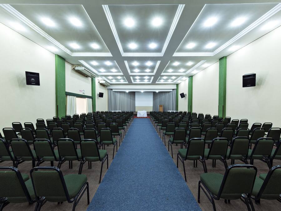 A conference room with rows of chairs, a blue carpet, and a ceiling with recessed lighting.