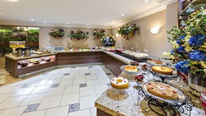 Un área de bufé con diversos alimentos, incluyendo pasteles y frutas, dispuestos sobre una encimera de mármol.