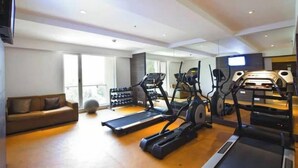 Ein moderner Fitnessraum mit Laufbändern, Crosstrainern und Kurzhanteln.