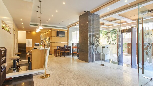 Eine moderne Hotelhalle mit Empfangstresen, Sitzgelegenheiten und einem großen Spiegel.