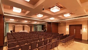 Ein Konferenzraum mit Stuhlreihen, einem Rednerpult und einem großen Spiegel an der Wand.