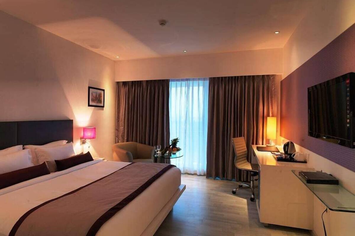 Een hotelkamer met een bed, bureau, stoel en een televisie.