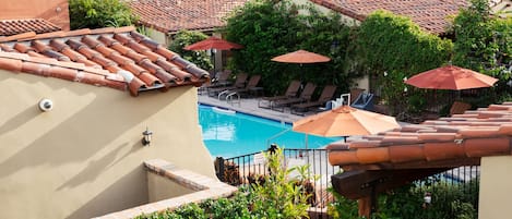 Zona de piscina en la azotea con techos de baldosas, sillas de descanso y sombrillas.