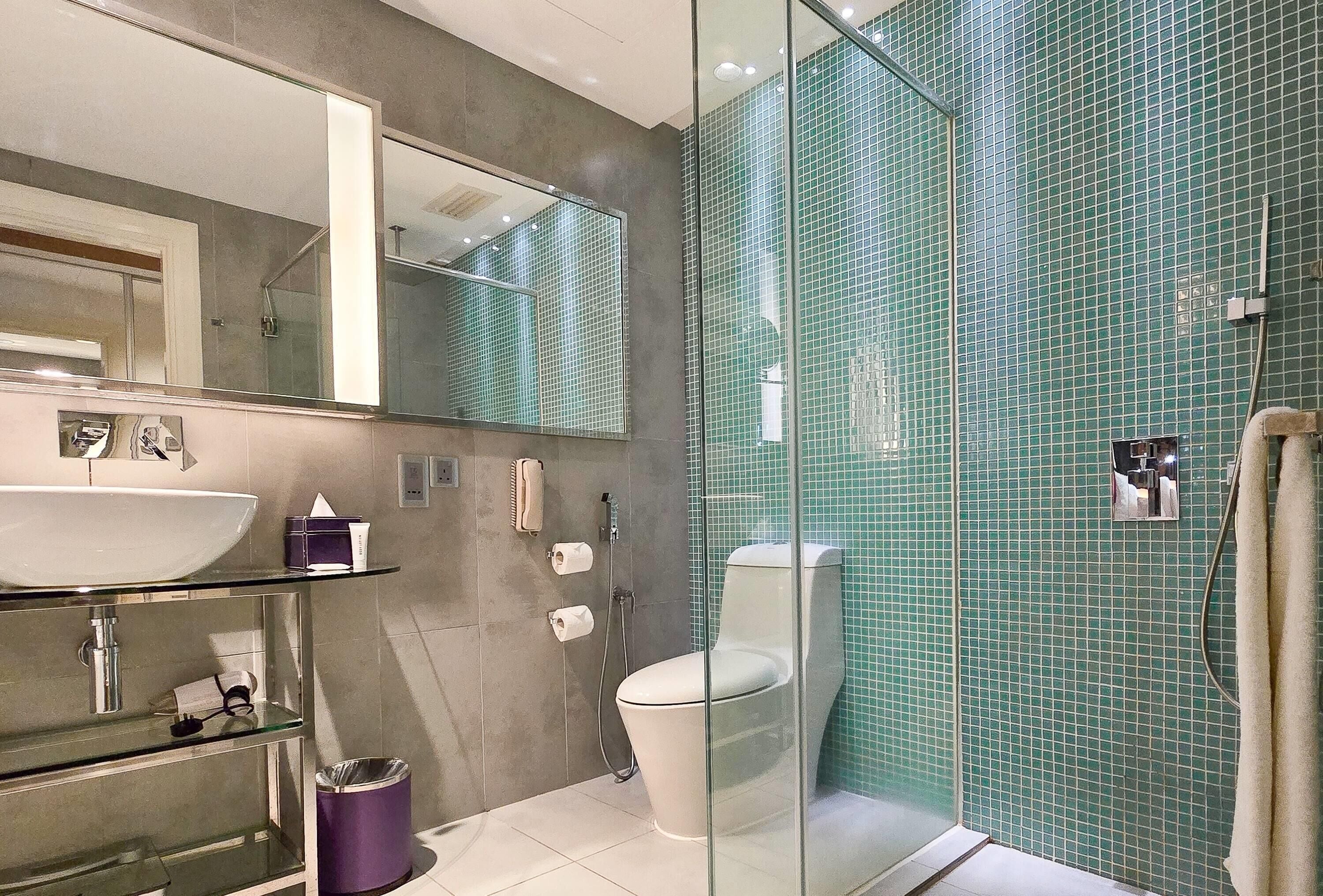 A modern bathroom with a glass-enclosed shower, a white sink, and a large mirror.