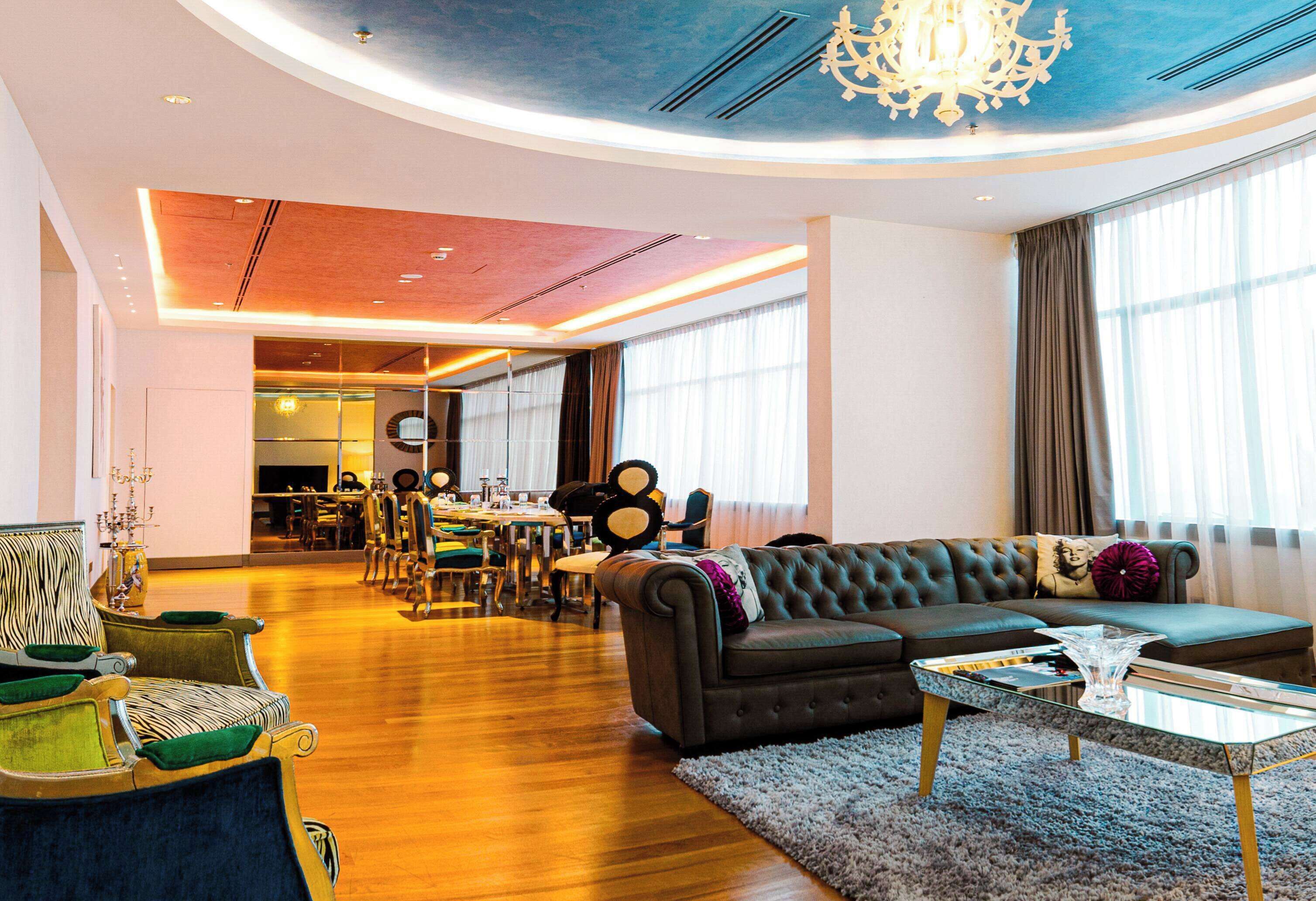 A spacious living area with a large sofa, a dining table, and a chandelier.