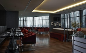 A modern dining area with wooden flooring, red upholstered chairs, and a long table set for dining. - Wyndham Grand Bangsar Kuala Lumpur (Kuala Lumpur)