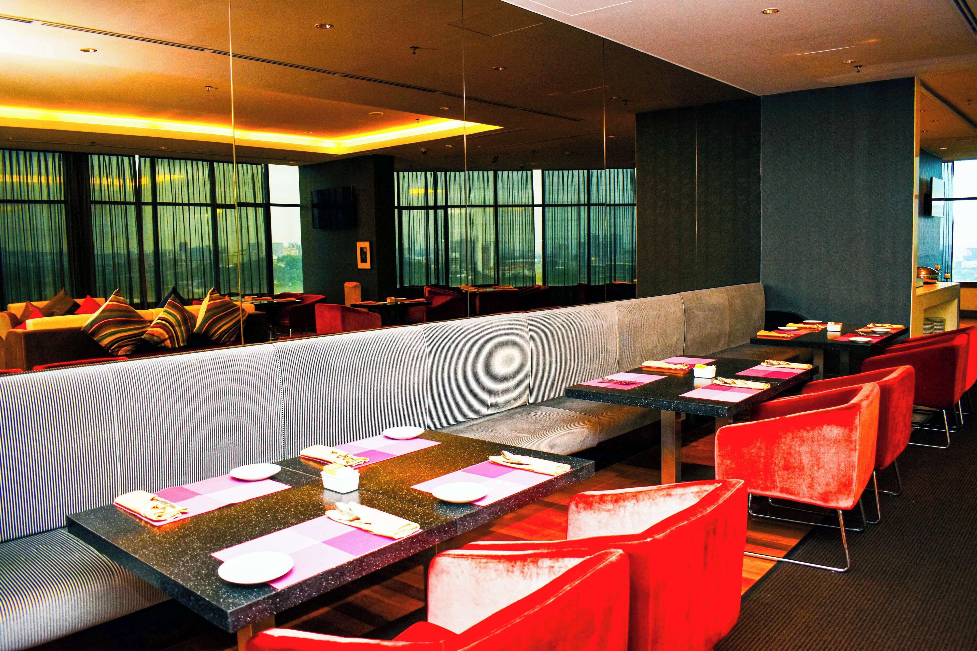 Un restaurante con una amplia zona de asientos compartidos, mesas individuales y sillas rojas.