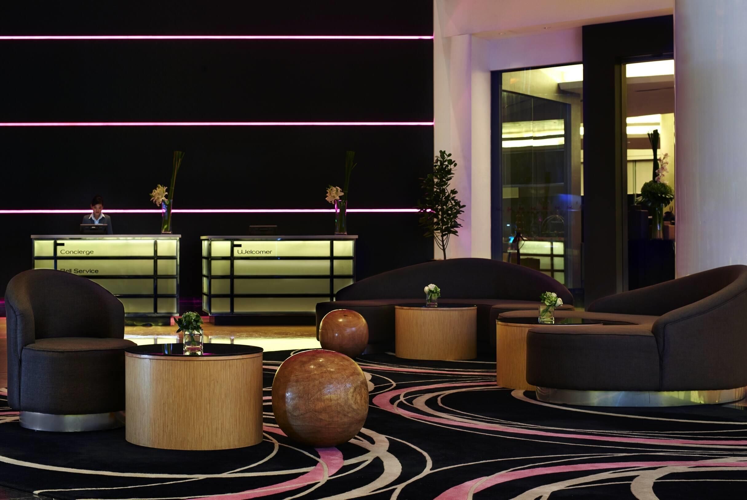 Um lobby moderno com áreas de estar, um balcão de recepção e um vaso decorativo.