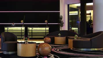 Um lobby moderno com áreas de estar, um balcão de recepção e um vaso decorativo.