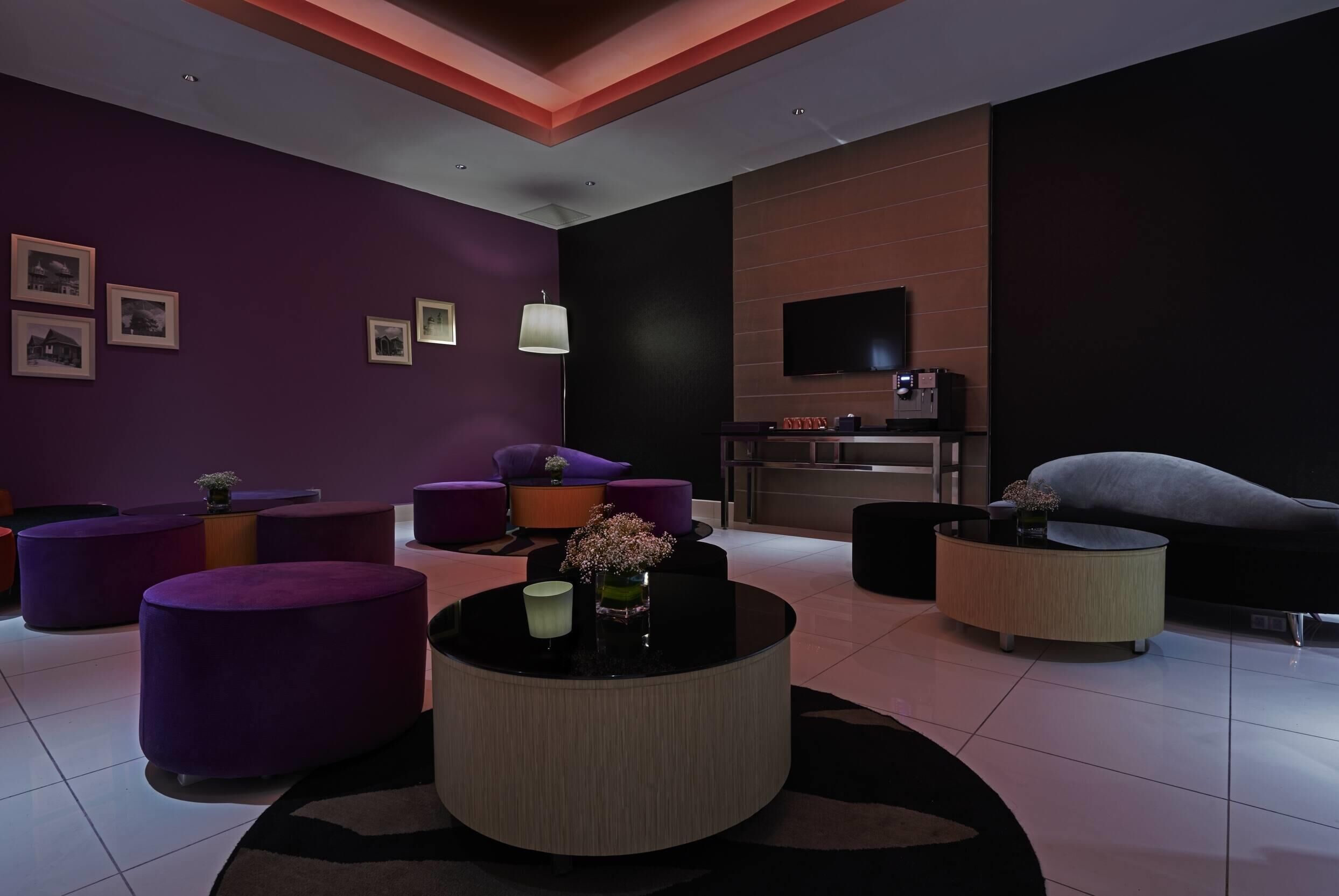 A modern living room with purple furniture, a flat-screen TV, and a fireplace.