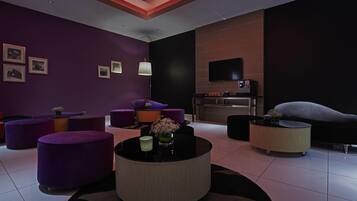 A modern living room with purple furniture, a flat-screen TV, and a fireplace.