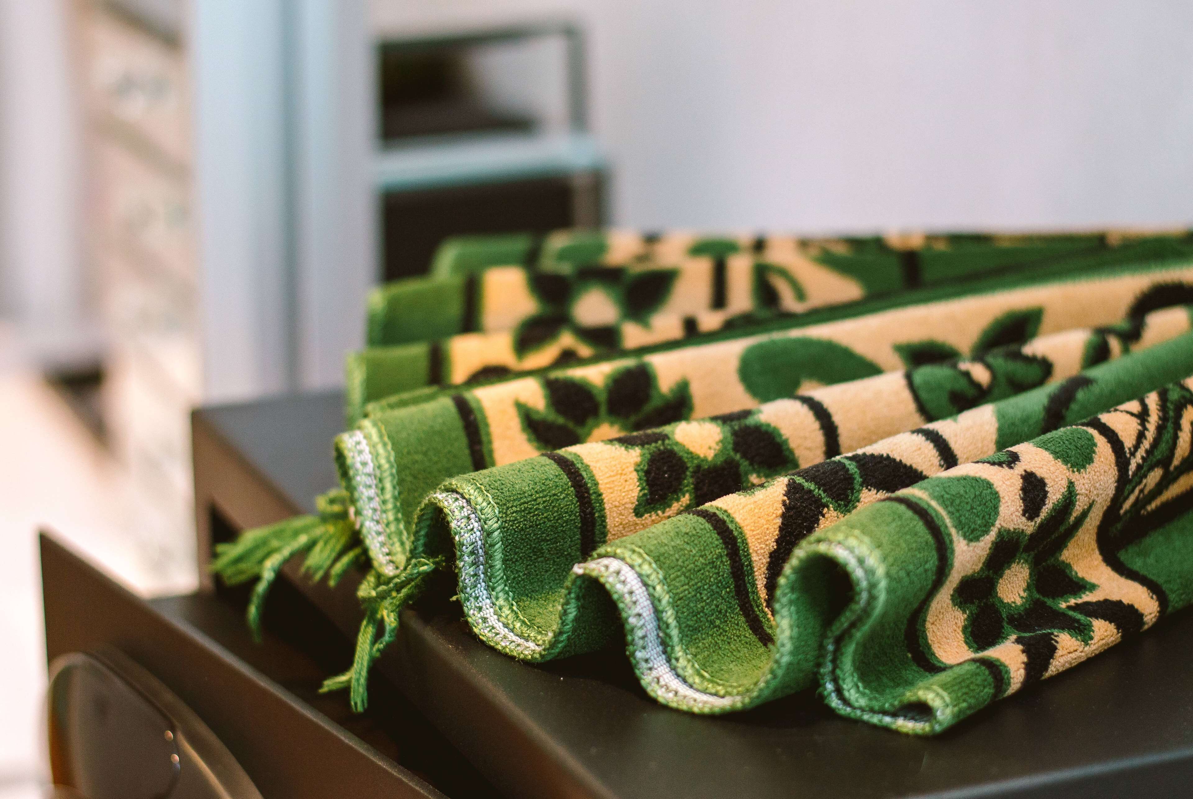 A stack of green and beige patterned towels on a dark surface.