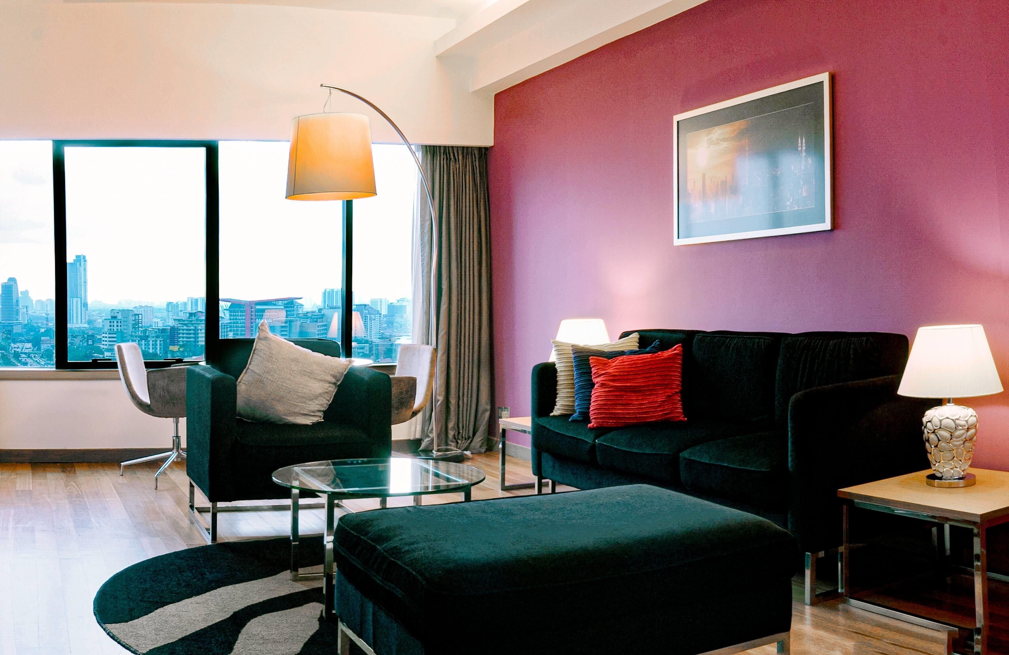 A modern living room with a city view, two sofas, a glass coffee table, and a lamp.
