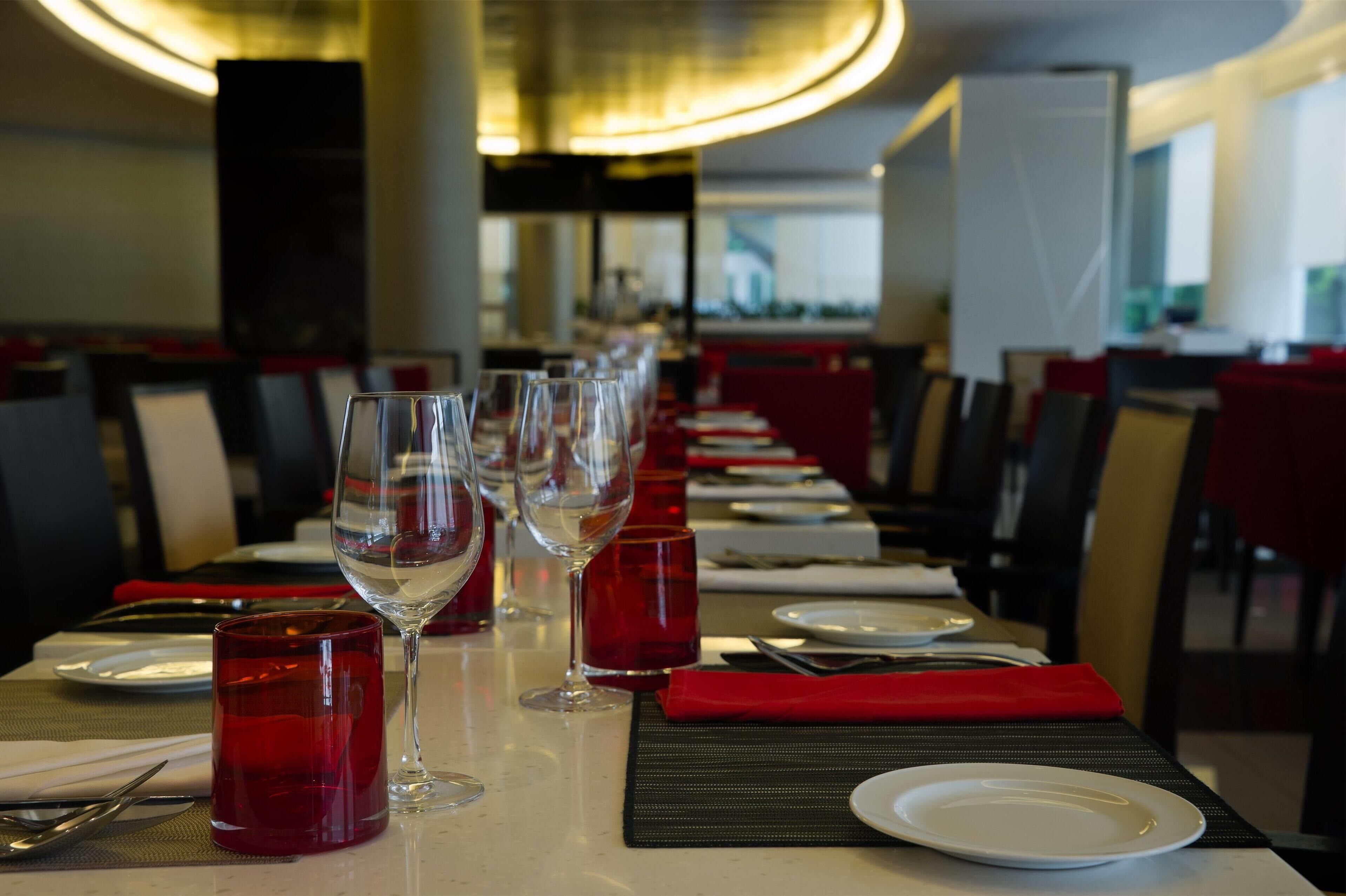A restaurant setting with a long table set for dining, including plates, glasses, and cutlery.