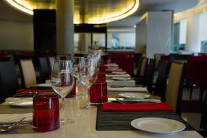 Ein Restaurantambiente mit einem langen Tisch, gedeckt für ein Essen, inklusive Teller, Gläsern und Besteck.