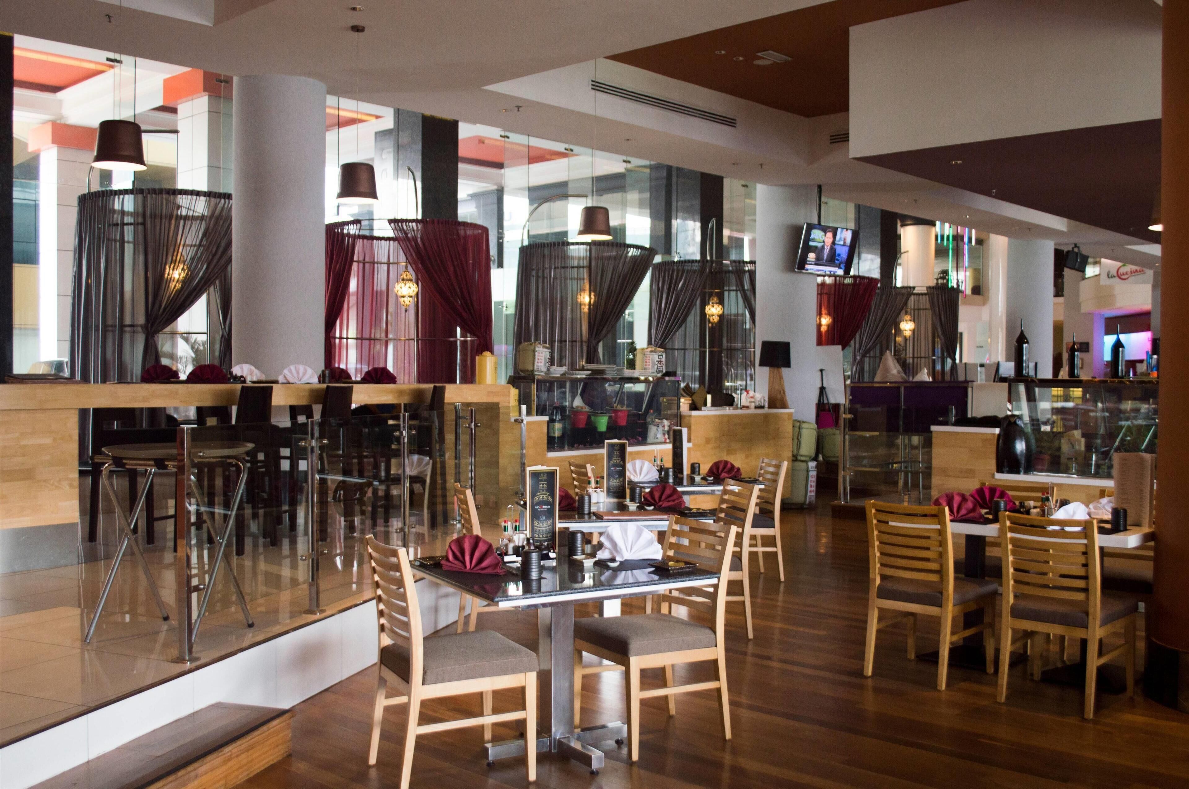 Un restaurante moderno con divisiones de vidrio, sillas de madera y una zona de bar.
