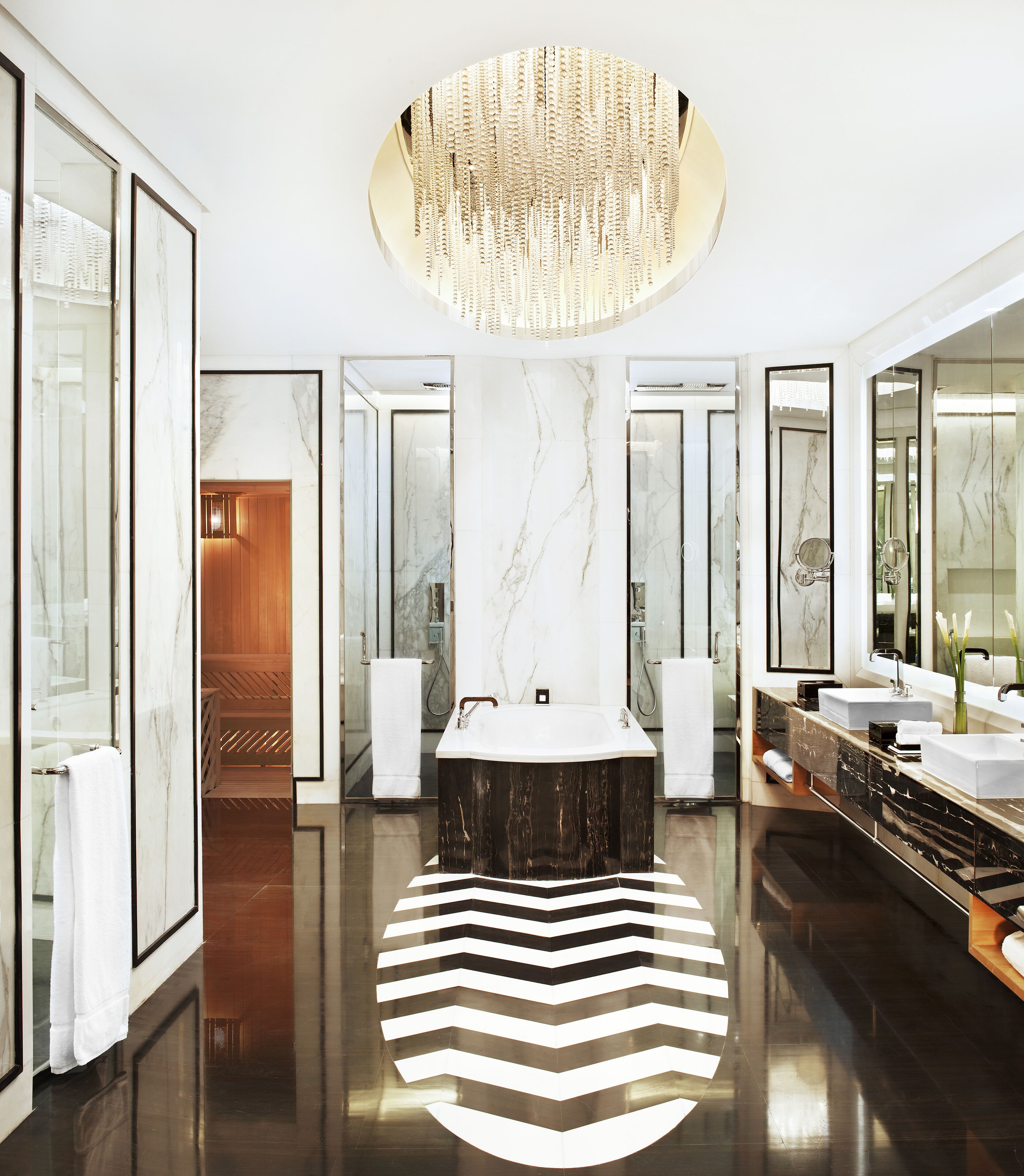 A luxurious bathroom with a large central sink, mirrored walls, and a distinctive black and white striped floor.