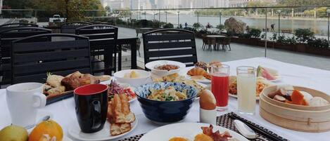 A table set with breakfast items and a view of a river and cityscape.
