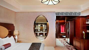Una habitación de hotel con una cama grande, un espejo redondo, un armario de madera y una alfombra estampada.