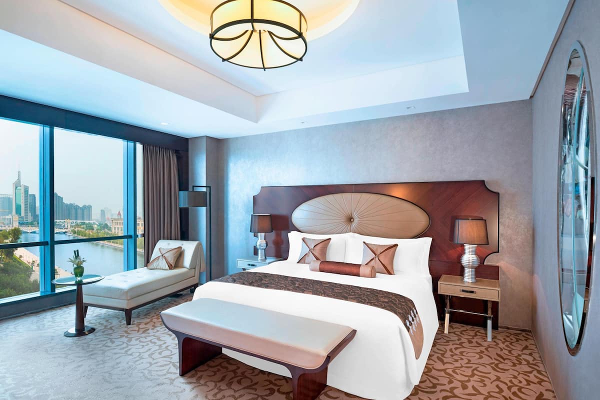 Ein modernes Hotelzimmer mit einem großen Bett, einer Sitzecke und Blick auf die Stadt.