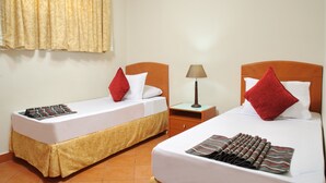 Two single beds with wooden headboards, white bedding, and red pillows. Each bed has a small wooden nightstand with a lamp. -  Golf Porto Marina Hotel Apartments Al Alamein (El Alamein)