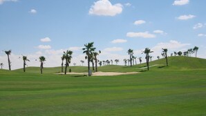 A golf course with green grass, palm trees, and a clear sky. -  Golf Porto Marina Hotel Apartments Al Alamein (El Alamein)