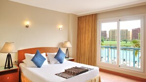 A hotel room with a bed, two bedside lamps, a view of the sea, and a balcony. -  Golf Porto Marina Hotel Apartments Al Alamein (El Alamein)
