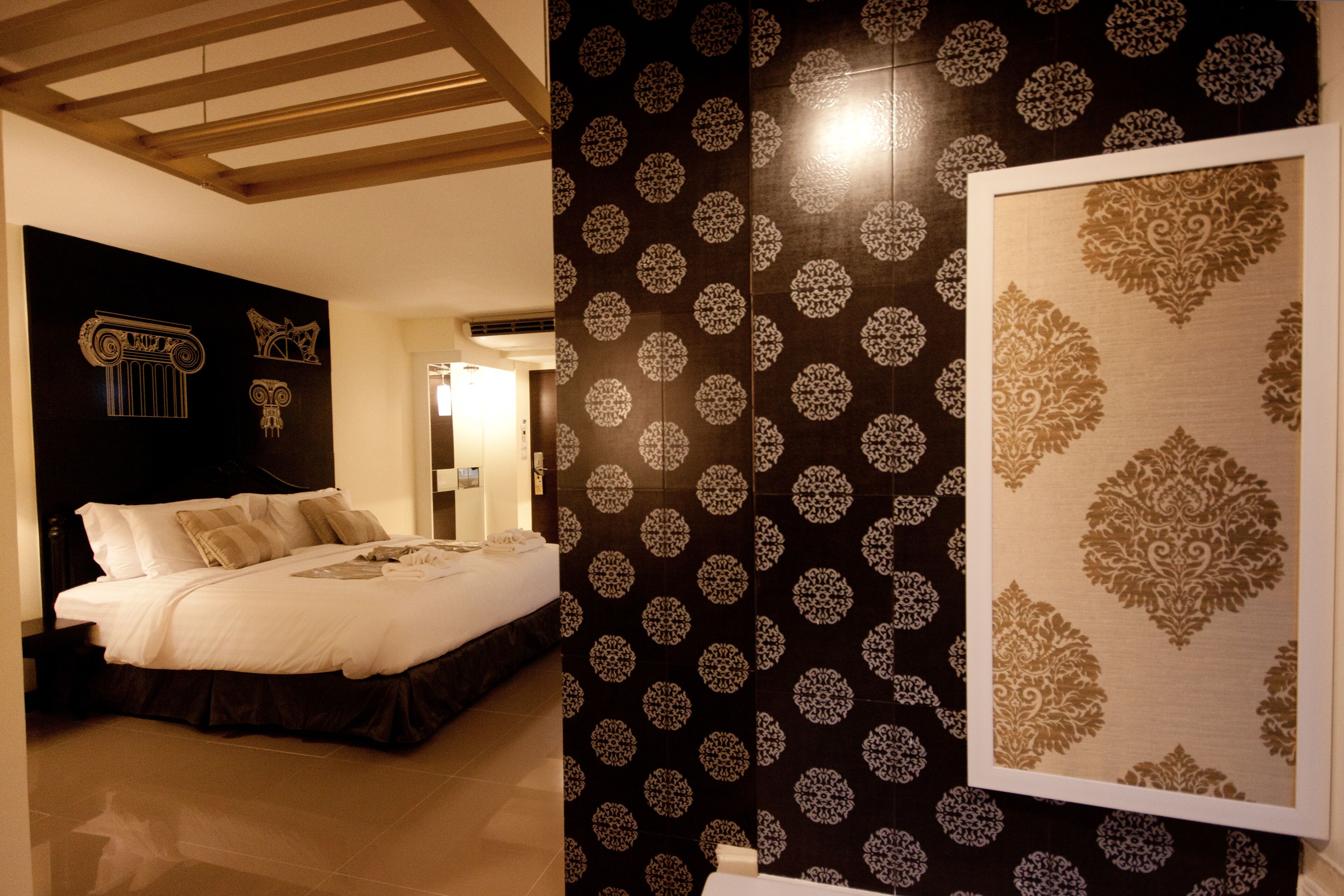 Ein Hotelzimmer mit Bett, Nachttisch, einer Wand mit strukturiertem Tapetenmuster und einem gerahmten Kunstwerk.