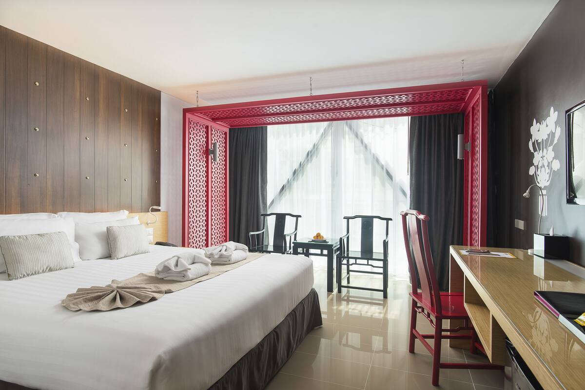 Une chambre d’hôtel avec un lit, un bureau et une chaise. Il y a une fenêtre avec des rideaux et une vue sur l’extérieur.