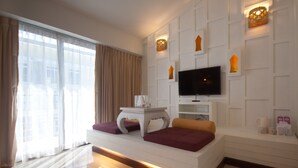 Een moderne hotelkamer met een flatscreen televisie aan de muur, een witte console en een bank met kussens.
